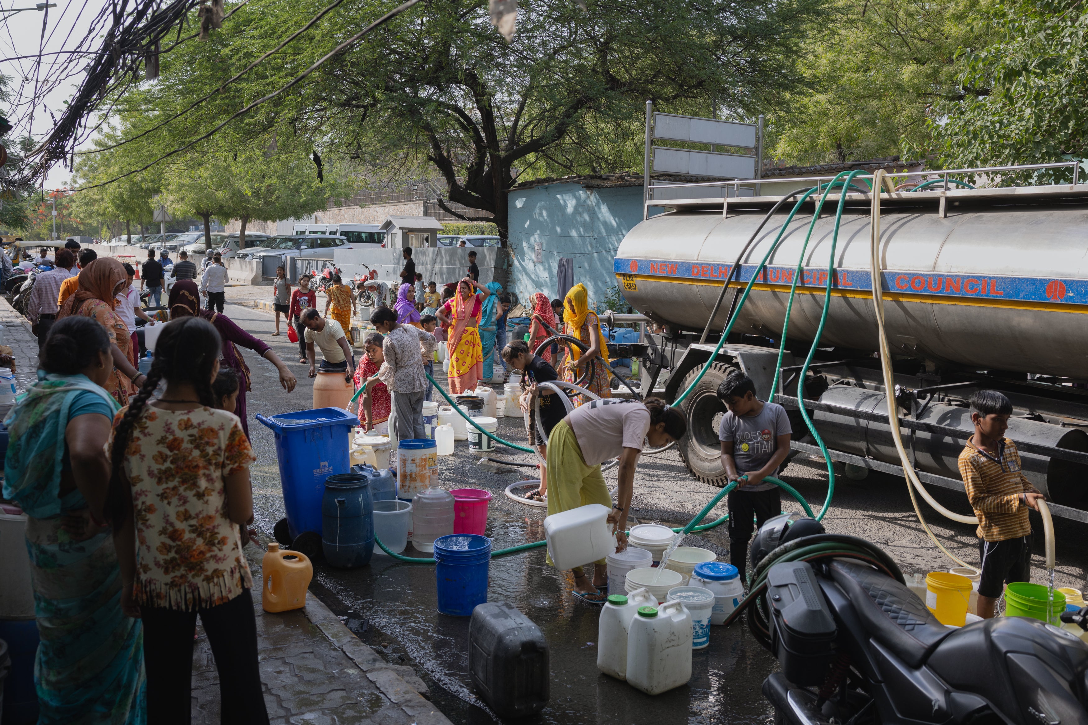Families fill up empty water buckets with potable water from the New Delhi Municipal Council water tanker in Delhi