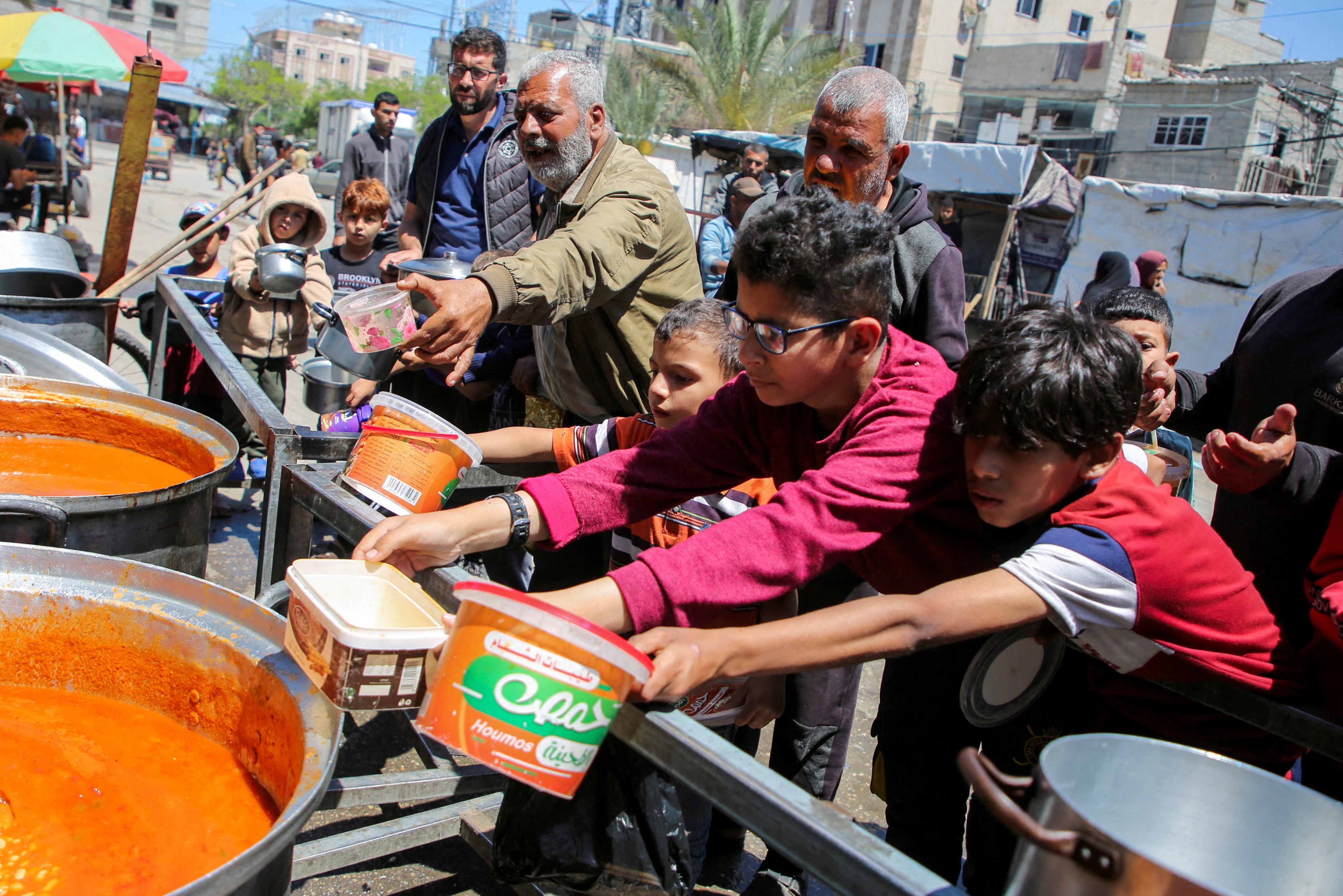 Palestinians gather to receive food cooked by a charity kitchen, amid shortages of aid supplies in Rafah