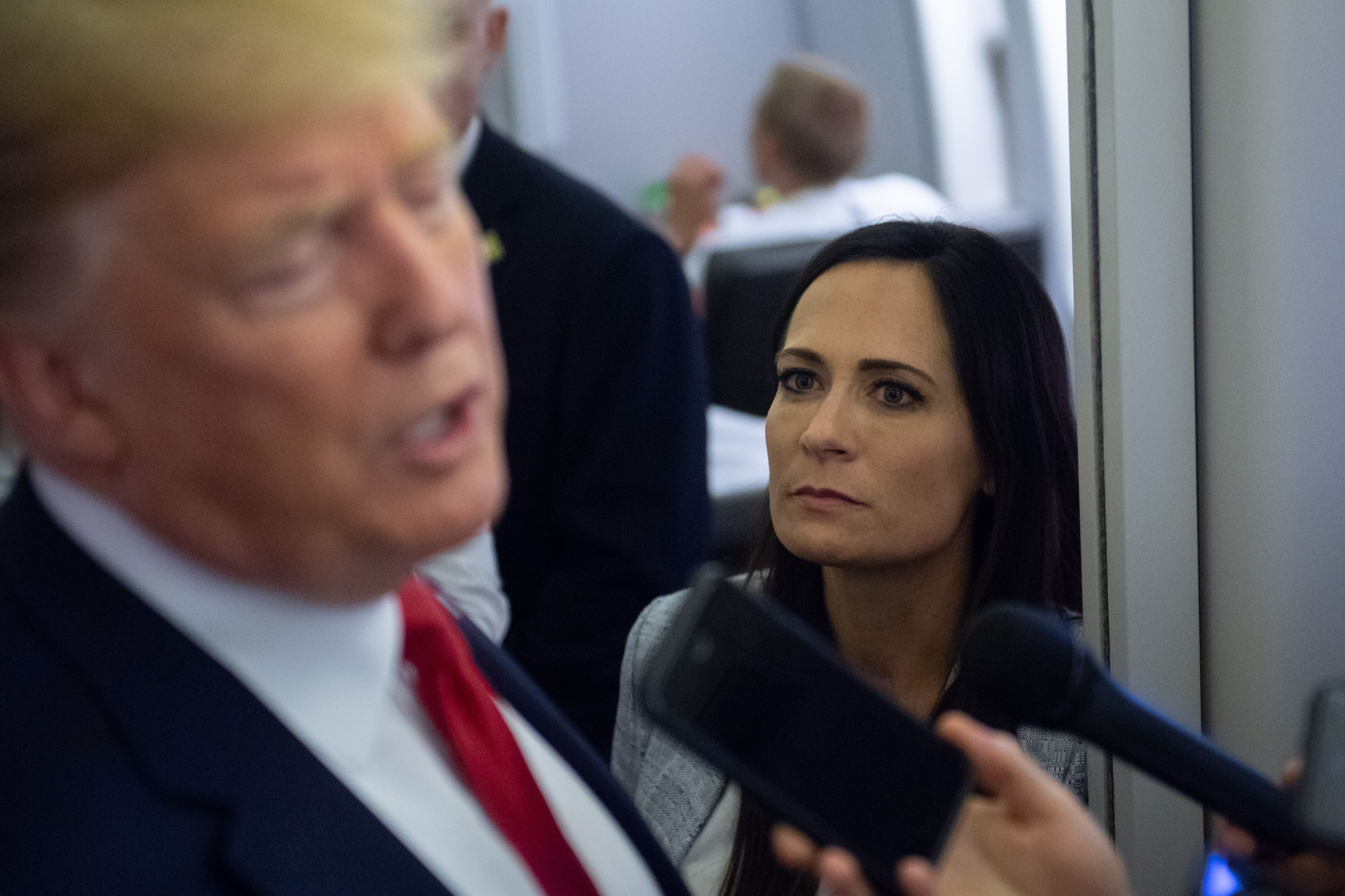 White House Press Secretary Stephanie Grisham listens as US President Donald Trump speaks to the media aboard Air Force One in 2019
