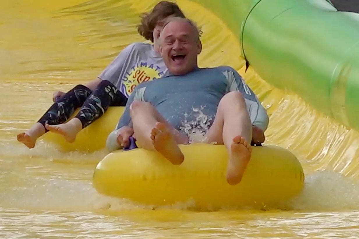 Liberal Democrat leader Sir Ed Davey rides down the Ultimate Slip n Slide attraction near Frome, Somerset, while on the General Election campaign trail (Rod Minchin/PA)