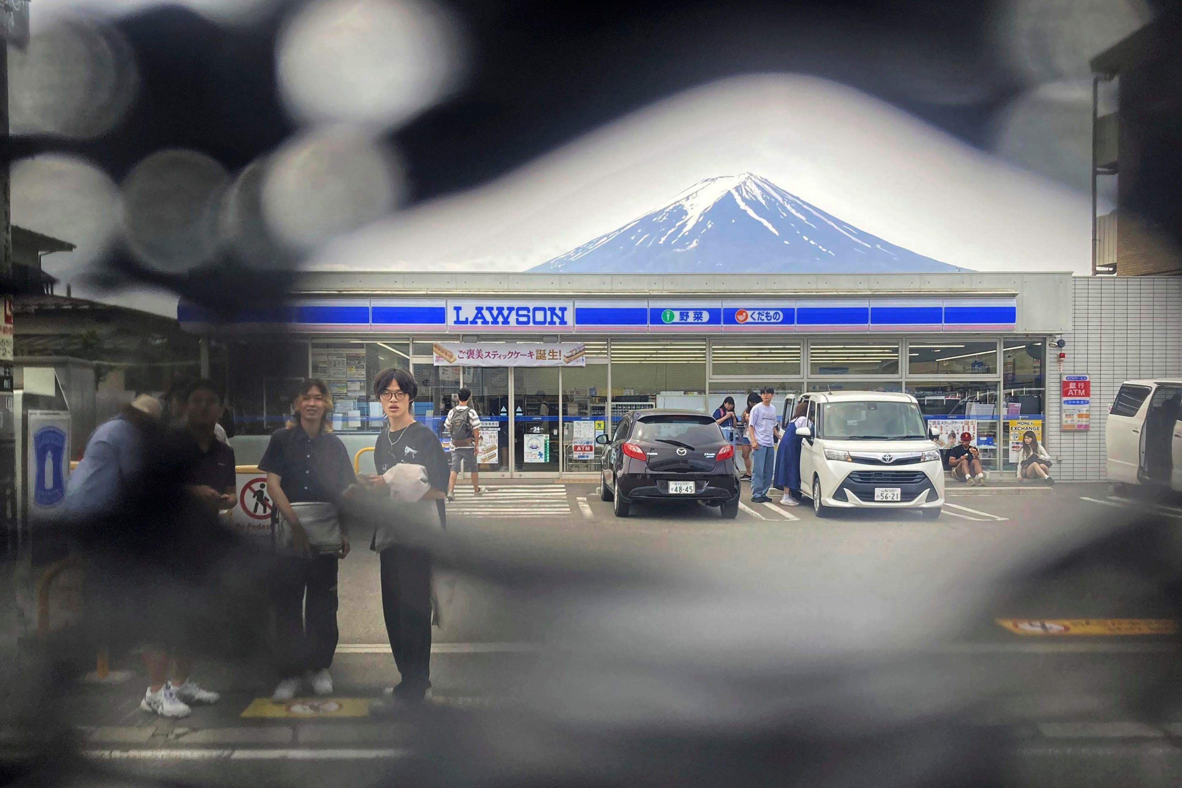 Mount Fuji is seen through a hole on a black screen installed across from a convenience store in Fujikawaguchiko town in central Japan