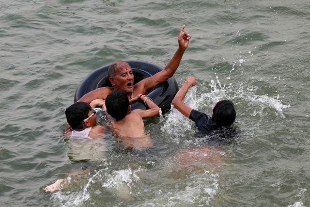 <p>A man teaches children to swim in the Ganges river on a hot summer afternoon in the northern city of Varanasi</p>