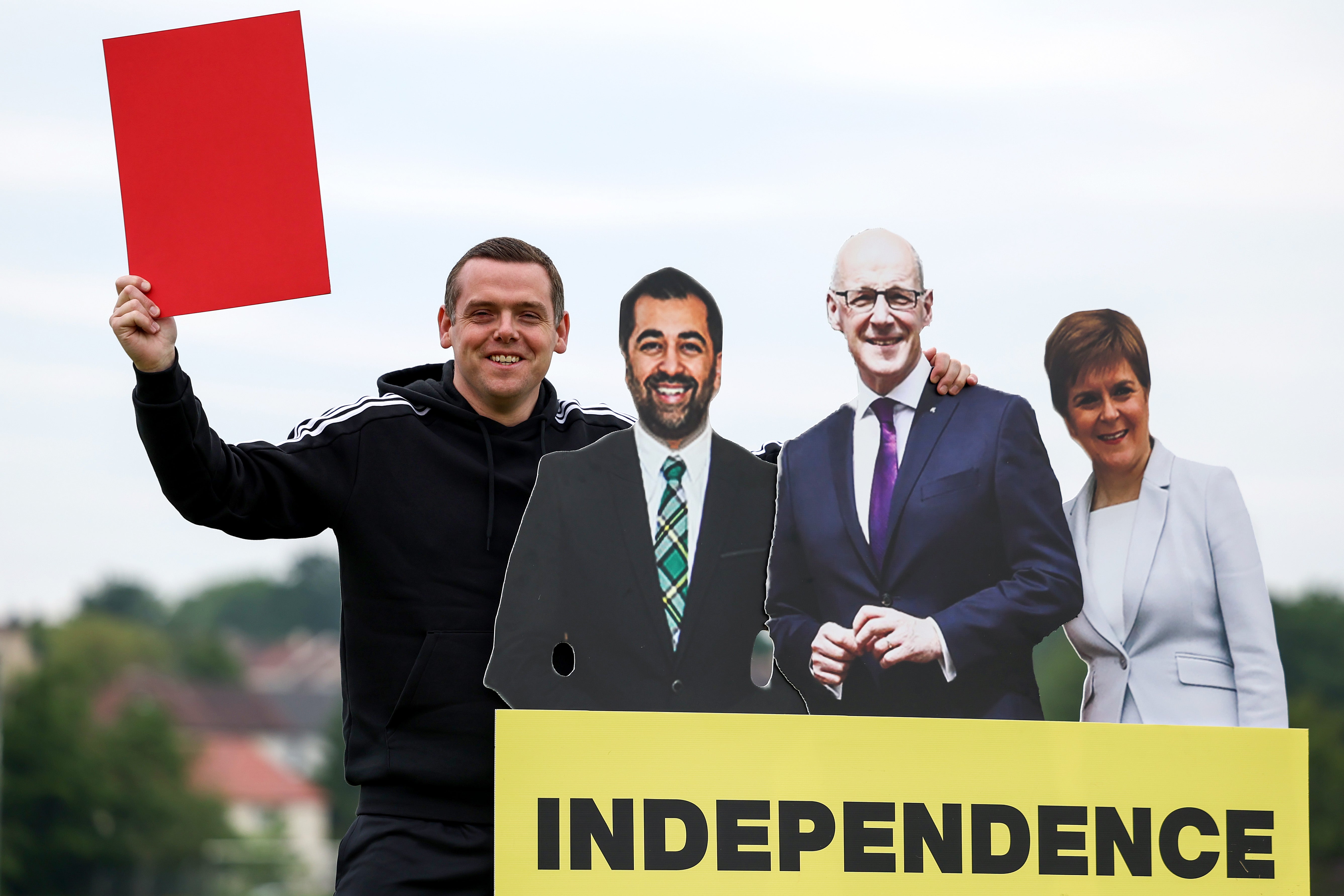 Scottish Conservative leader Douglas Ross holds up a red card to cardboard cutouts of John Swinney, Humza Yousaf and Nicola Sturgeon during an election campaign event