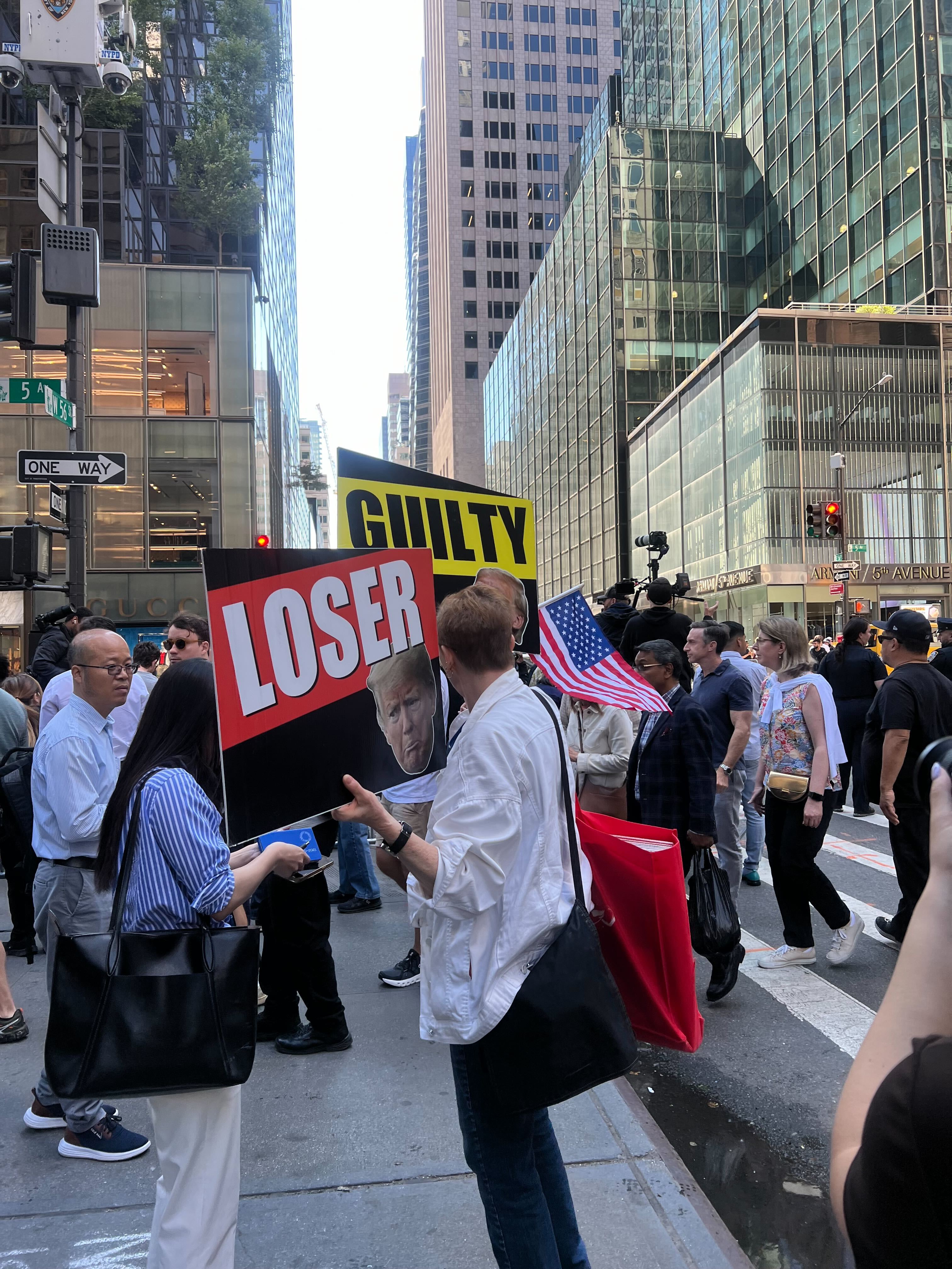 An opponent of former President Donald Trump holds signs outside Trump Tower on 31 May