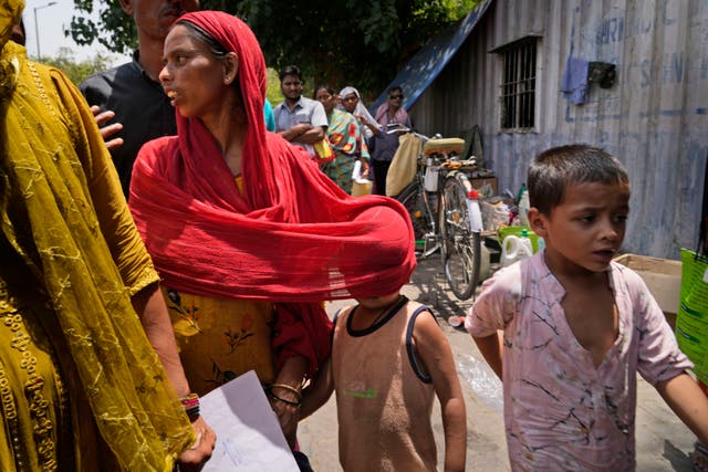 <p>A woman covers a child with her scarf to protect him from the sun as a heat wave grips the Indian capital New Delhi</p>