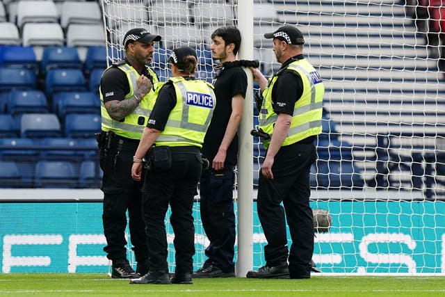 Police speak to a protester who chained themselves to a goalpost (Jane Barlow/PA)