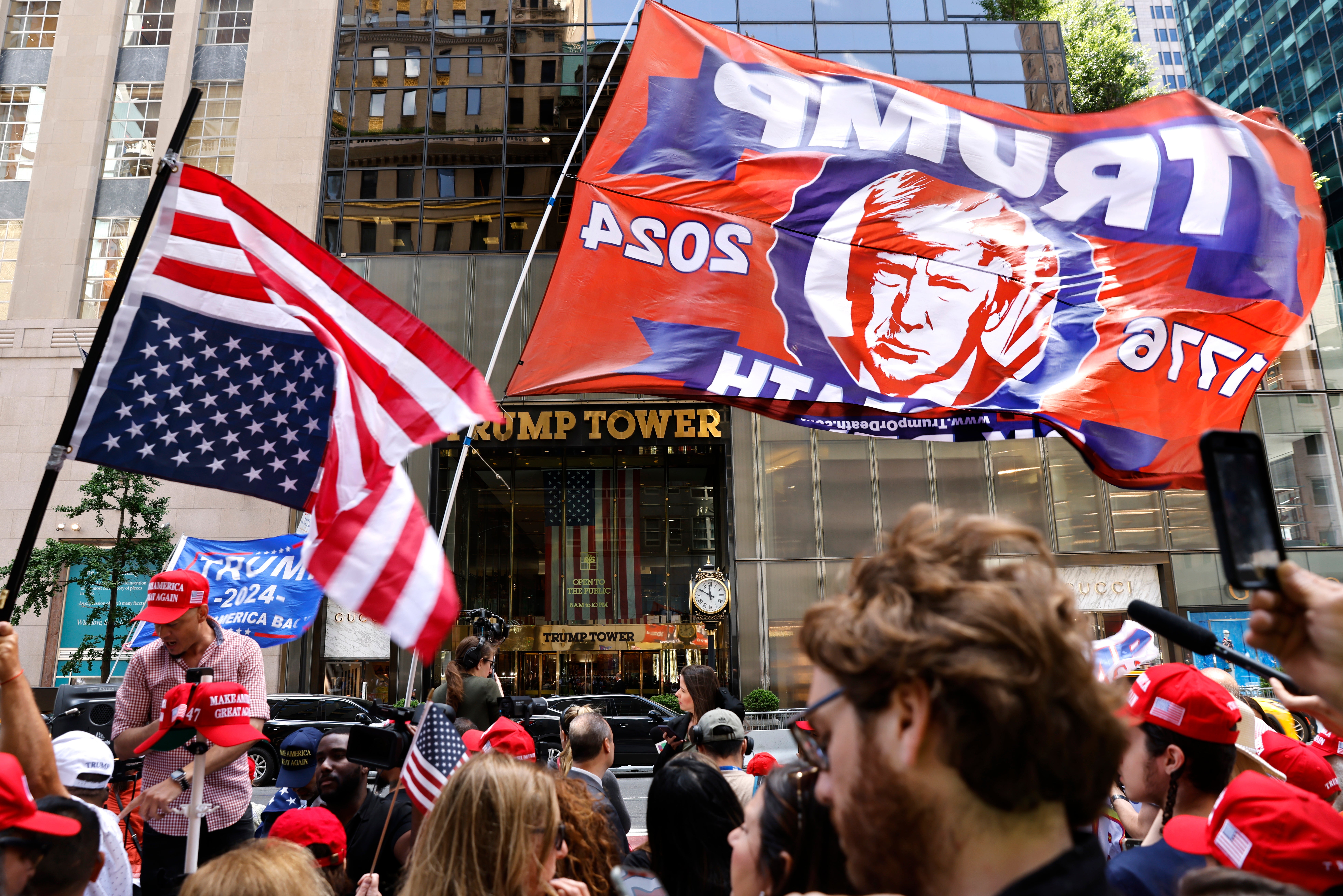 Supporters of former president Donald Trump wave banners after Trump spoke at a press conference at Trump Tower the day after a jury found him guilty on all 34 counts in his hush money criminal trial. A new poll shows nearly half of independent voters think Trump should now end his presidential campaign