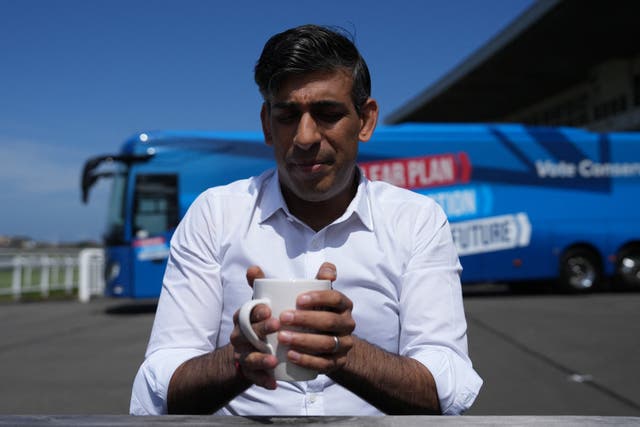 <p>Britain's Prime Minister and Conservative Party leader Rishi Sunak holds a mug while speaking to journalists at Redcar racecourse</p>