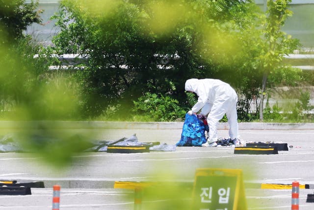 <p>An official collects the debris of a balloon sent by North Korea at a shopping centre in Siheung, west of Seoul, South Korea, 2 June 2024</p>