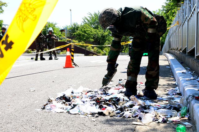 <p>South Korean soldier wearing protective gears checks the trash from a balloon presumably sent by North Korea, in Incheon, South Korea, on Sunday</p>
