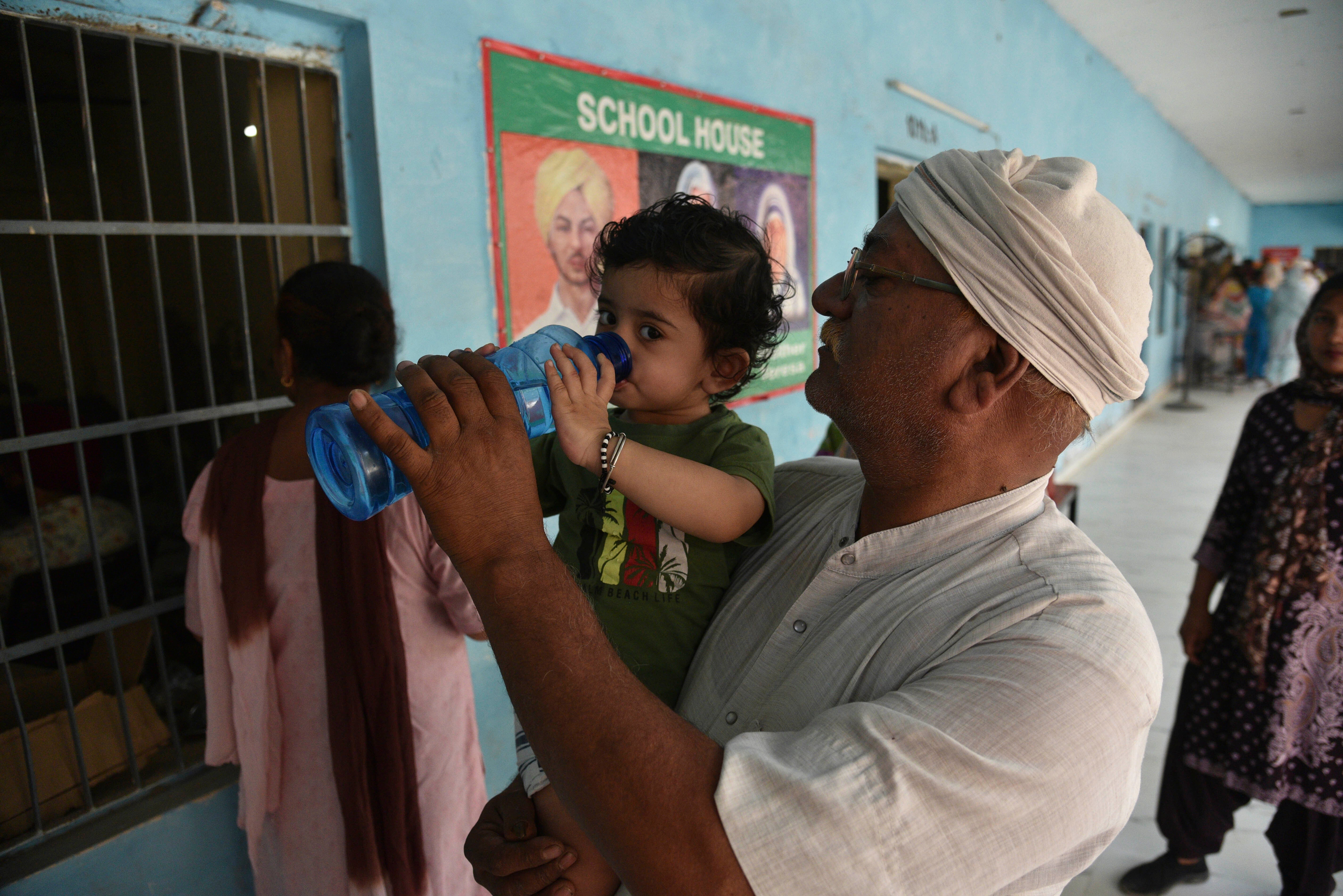 <p>A voter helps his child to drink water while waiting to cast his vote on a hot summer day during the seventh and the last phase of general election, near Amritsar, India</p>