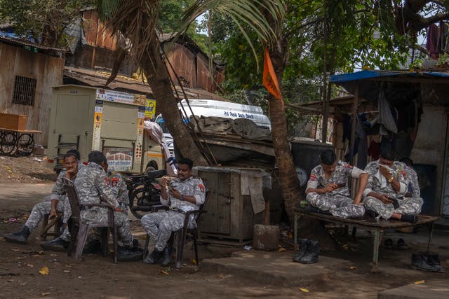 <p>Soldiers sit under the shade of a tree outside a vote-counting centre in Mumbai on Monday</p>