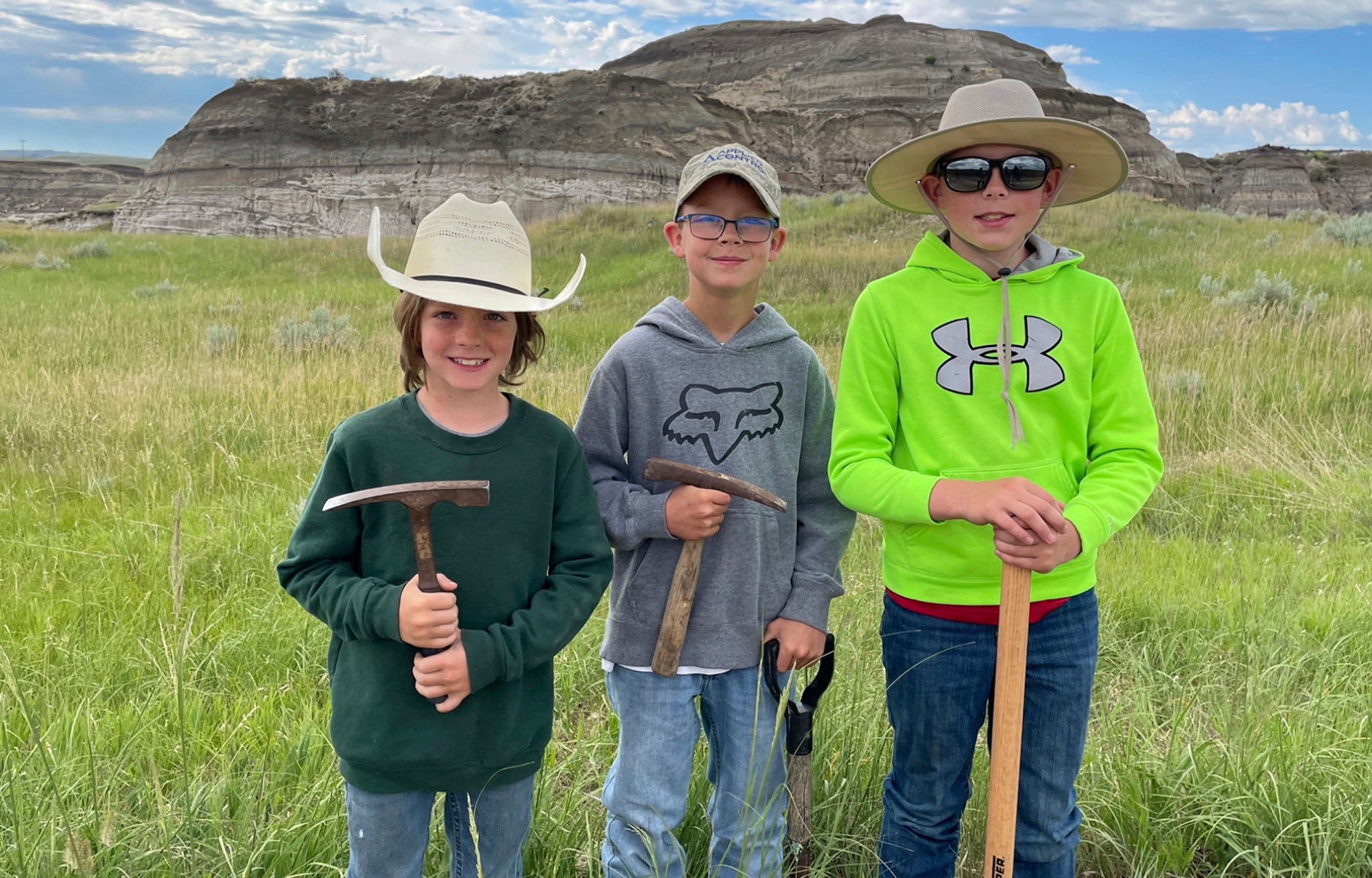 In this image provided by Giant Screen Films, Liam Fisher, Kaiden Madsen and Jessin Fisher pose for a celebratory photo on the day their fossil find was determined to be a juvenile T rex, in North Dakota