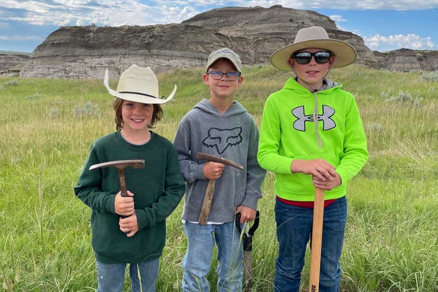 <p>In this image provided by Giant Screen Films, Liam Fisher, Kaiden Madsen and Jessin Fisher pose for a celebratory photo on the day their fossil find was determined to be a juvenile T rex, in North Dakota</p>
