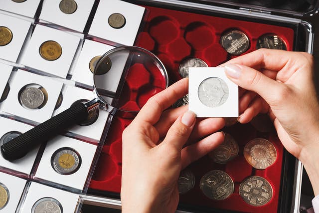 <p>A box with collectible coins in cells and a hand holding a coin. According to a May YouGov poll of nearly 3,000 American adults, over 80 percent reported they would stop to pick up coins on the street, with the habit being common among older adults. </p>