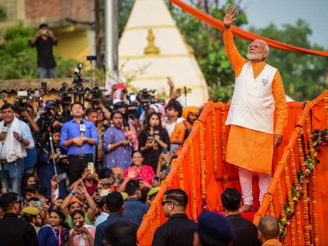 <p>Indian prime minister Narendra Modi greets supporters during his roadshow on 13 May 2024 in Varanasi, India</p>