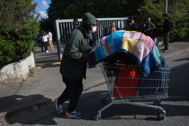 <p>A migrant walks with his belongings stored in a trolley to take a bus for another reception centre, during the evacuation of France’s biggest squat, which has housed up to 450 migrants, most of them legal migrants according to associations - in the southern suburbs of Paris in Vitry-sur-Seine on 17 April </p>
