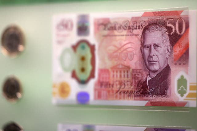 <p>Bank notes and coins that feature an image of Britain’s King Charles III are pictured on display</p>