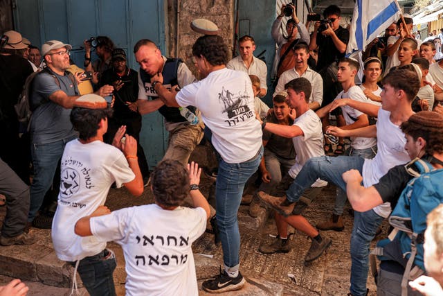 <p>Young men on the march grab a journalist during a march commemorating Jerusalem Day</p>