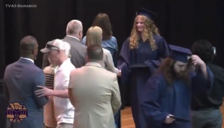 An unnamed father of a graduate is pictured shoving Superintendent Rainey Briggs (far left) off the stage. In 2018, the same high school made national news after a photo emerged of several students performing the Nazi salute