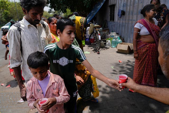 <p>Passersby stand in a queue to receive a cup of cold drink distributed by an organisation as a heat wave grips the Indian capital </p>