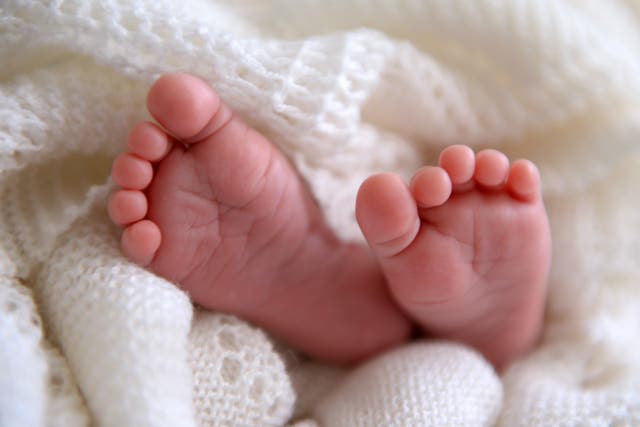 A new born baby’s feet are visible peeking out of a shawl (Andrew Matthews/PA)