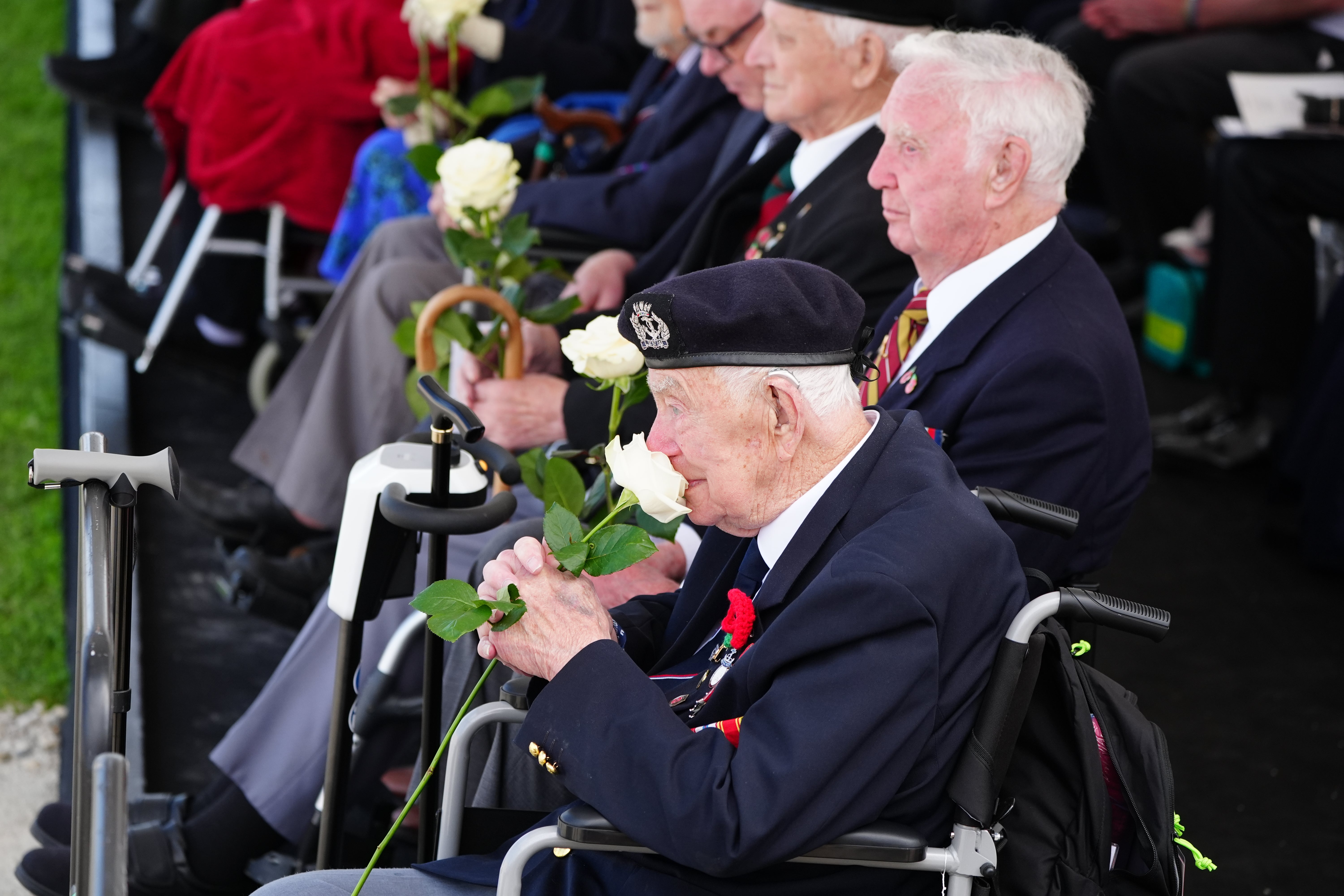 Veterans holding roses which they received from school children during the UK national commemorative event