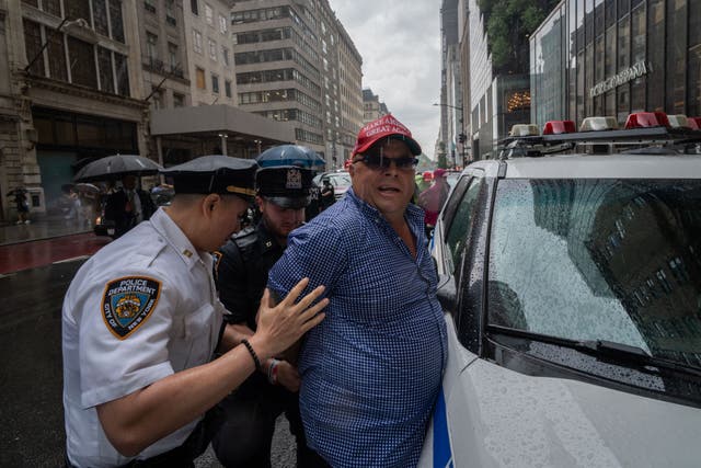 <p>Dion Cini is detained by New York City police officers outside Trump Tower on 6 June</p>