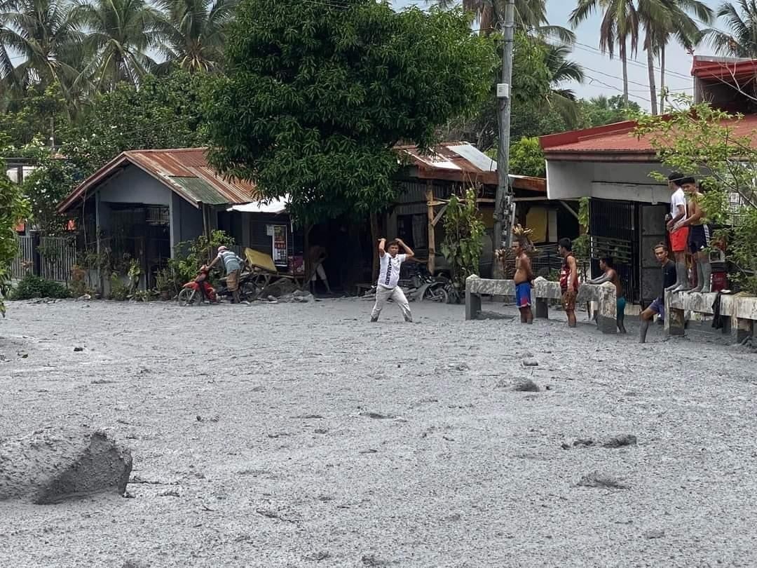 villagers wading through lahar from the eruption of Mount Kanlaon volcano at a village in the town of La Castellana