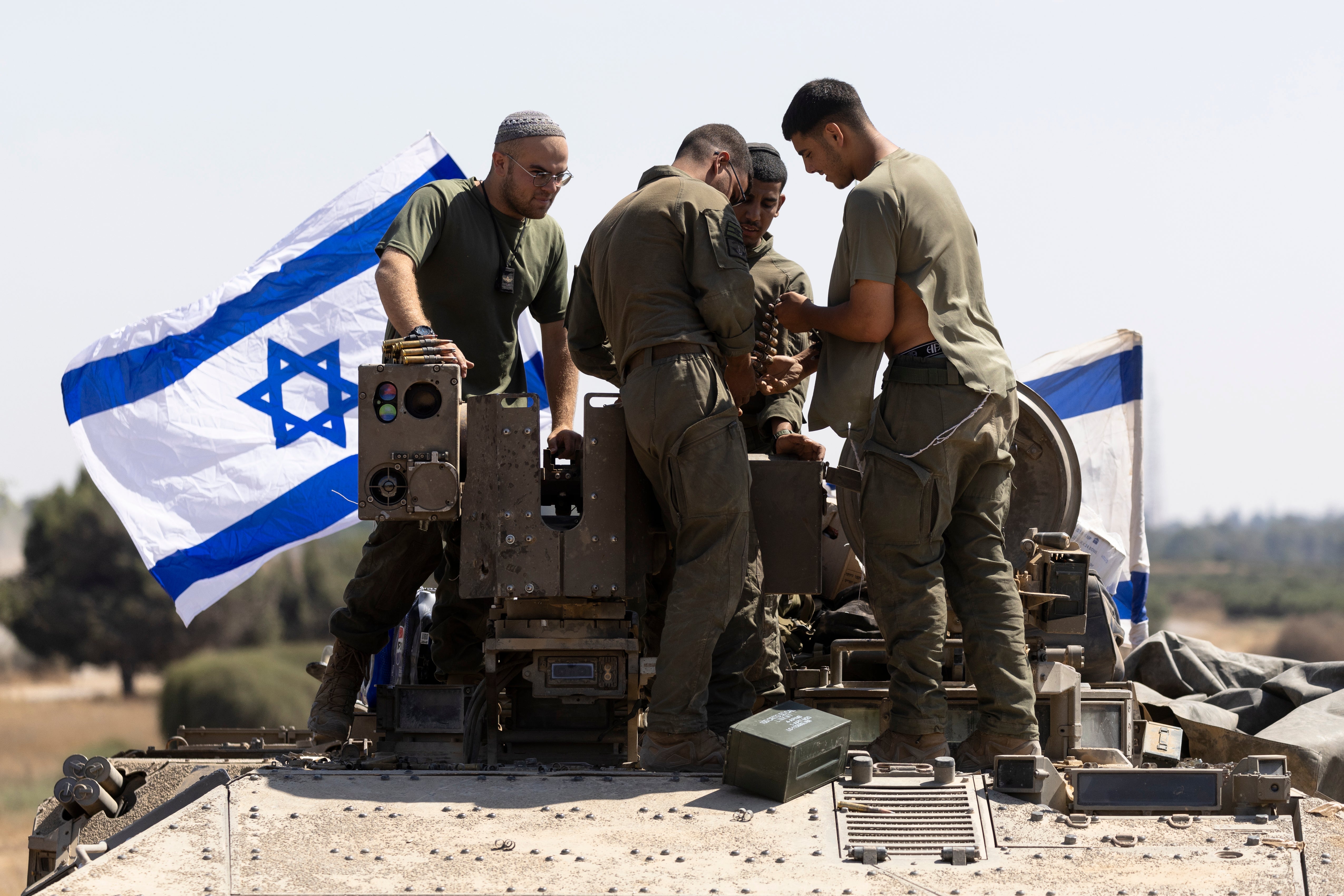 Israeli soldiers work with munitions on an armoured personnel carrier near the border with the Gaza Strip