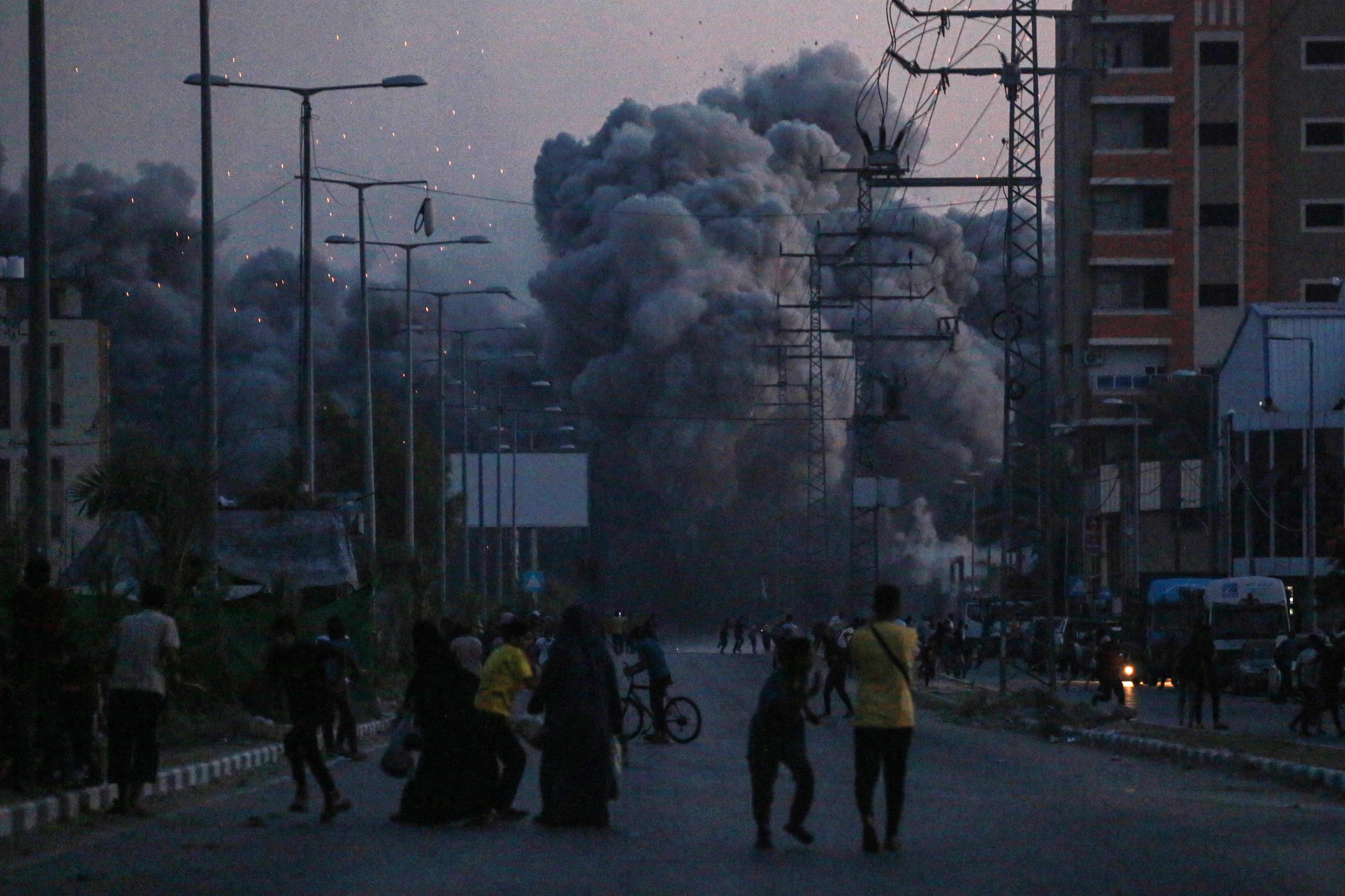 Palestinians watch smoke billowing following an Israeli airstrike in Deir al-Balah in the central Gaza Strip