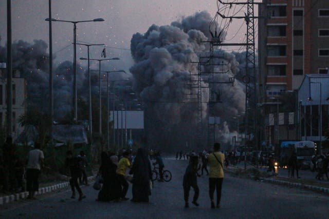 <p>Palestinians watch smoke billowing following an Israeli airstrike in Deir al-Balah in the central Gaza Strip</p>