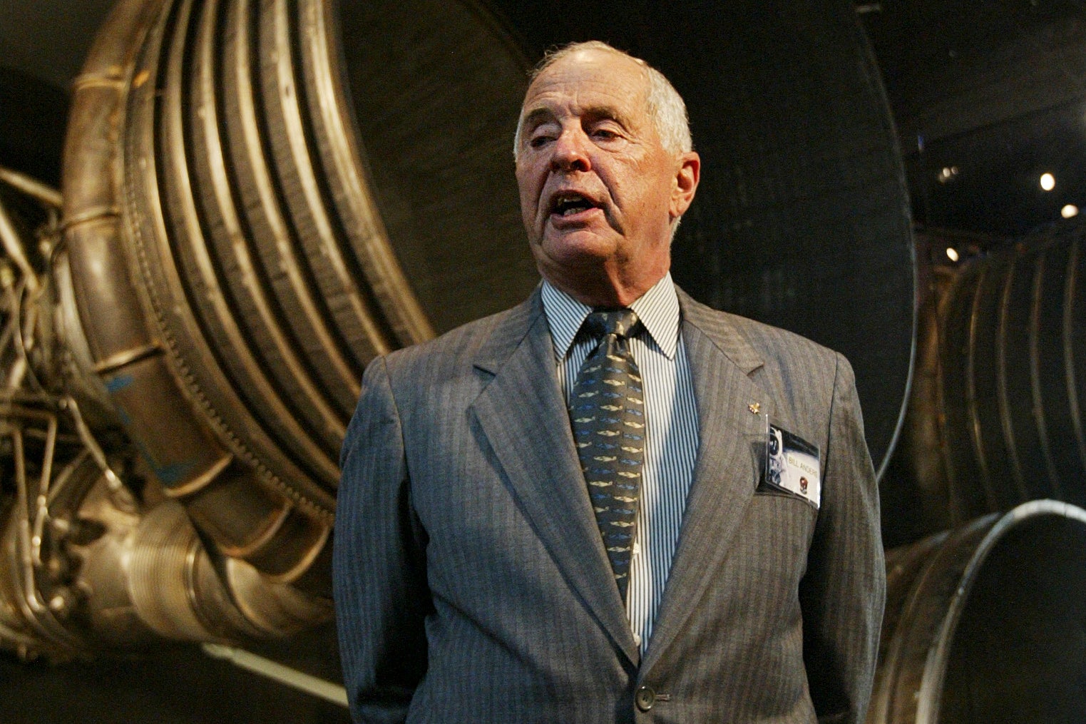 Apollo 8 Lunar Module Pilot Gen. William Anders, speaks to reporters in front of the Saturn 5 Aft End, the F-1 rocket engines of the first stage of the Apollo 11/Saturn 5 launch vehicle July 20, 2004, in Washington
