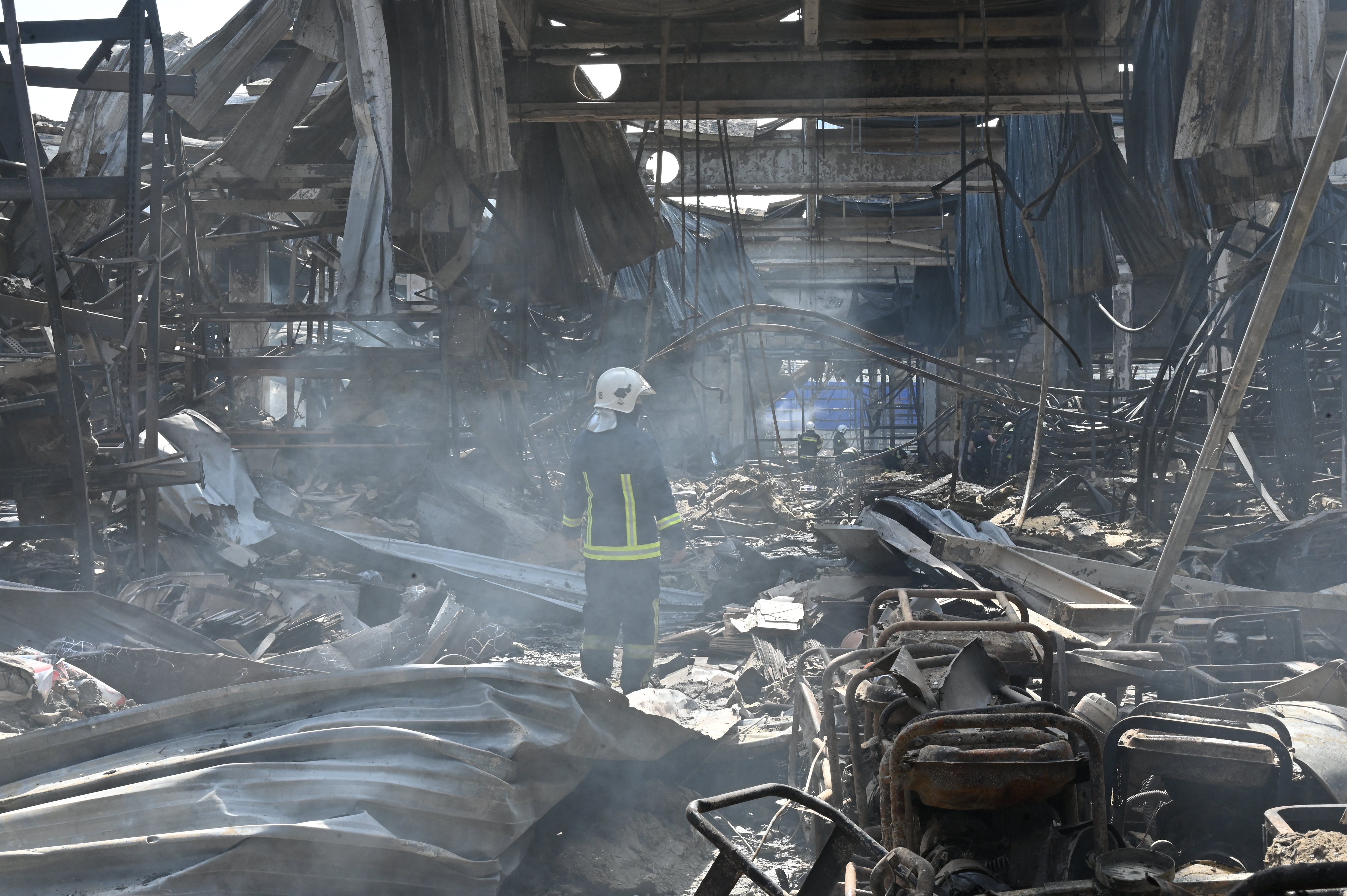 An employee of the State Emergency Service of Ukraine stands in the middle of debris in a hardware supermarket in Kharkiv destroyed by a Russian strike