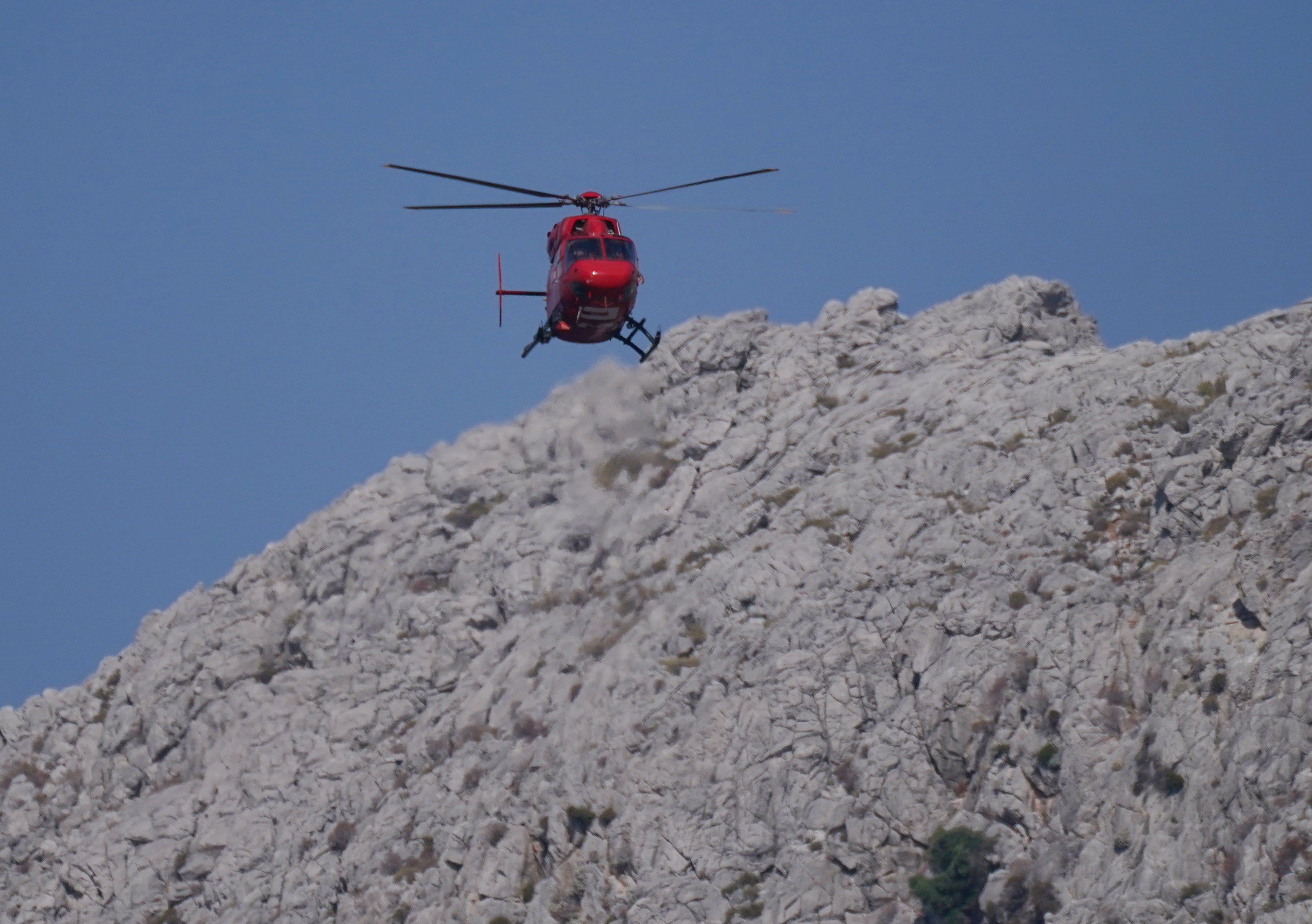 A helicopter flies over the hills in Pedi, Symi, Greece, as they search for Dr Mosley