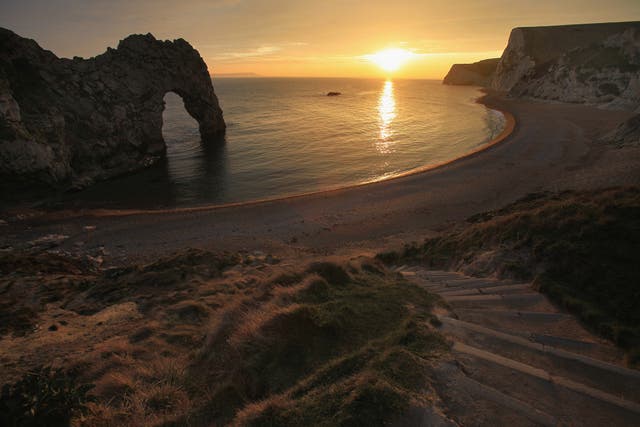 <p>The sun sets over the sea near Durdle Door in the English county of Dorset</p>