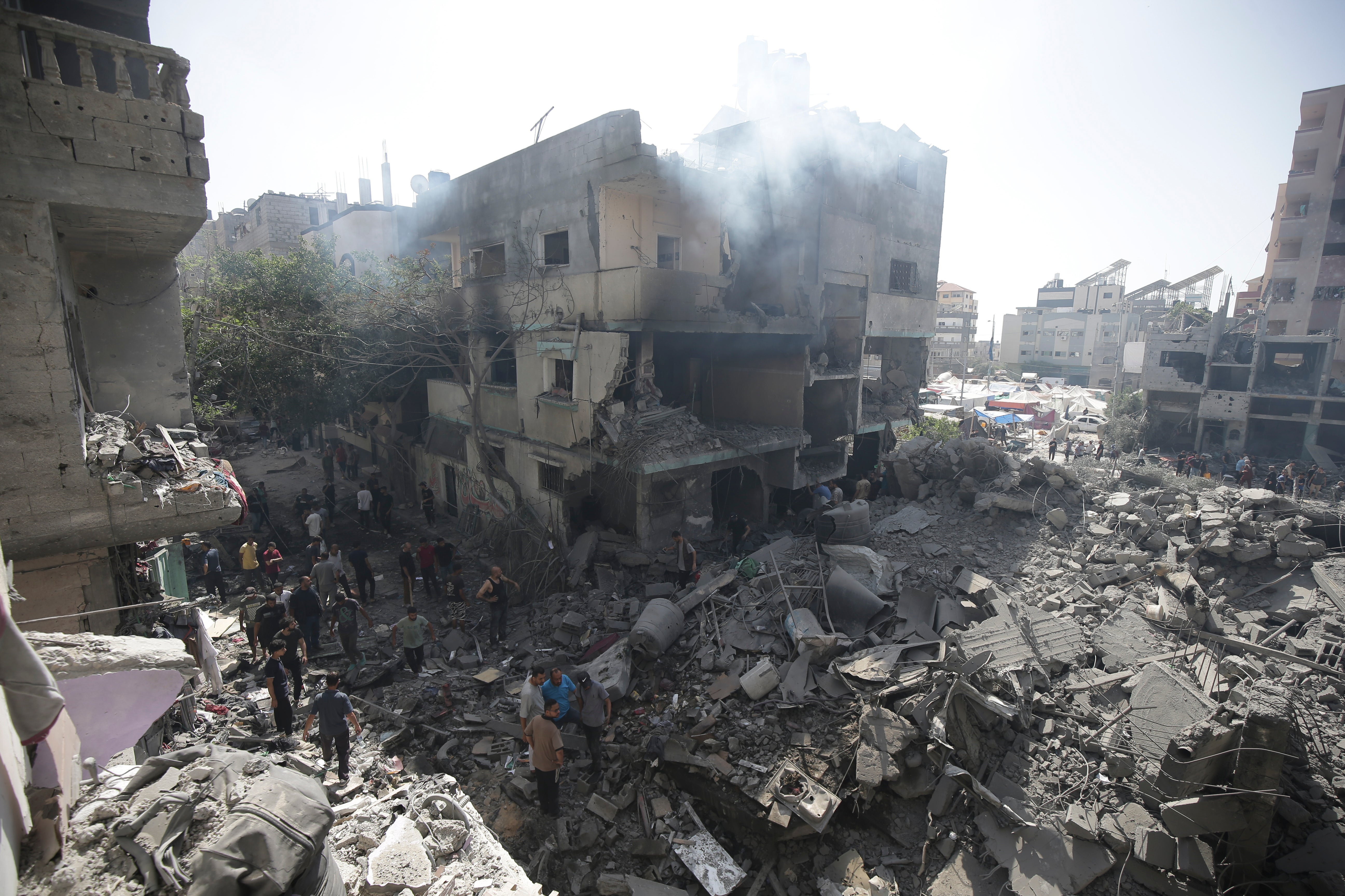 Palestinians look at the aftermath of the Israeli bombing of the Nuseirat refugee camp in Gaza