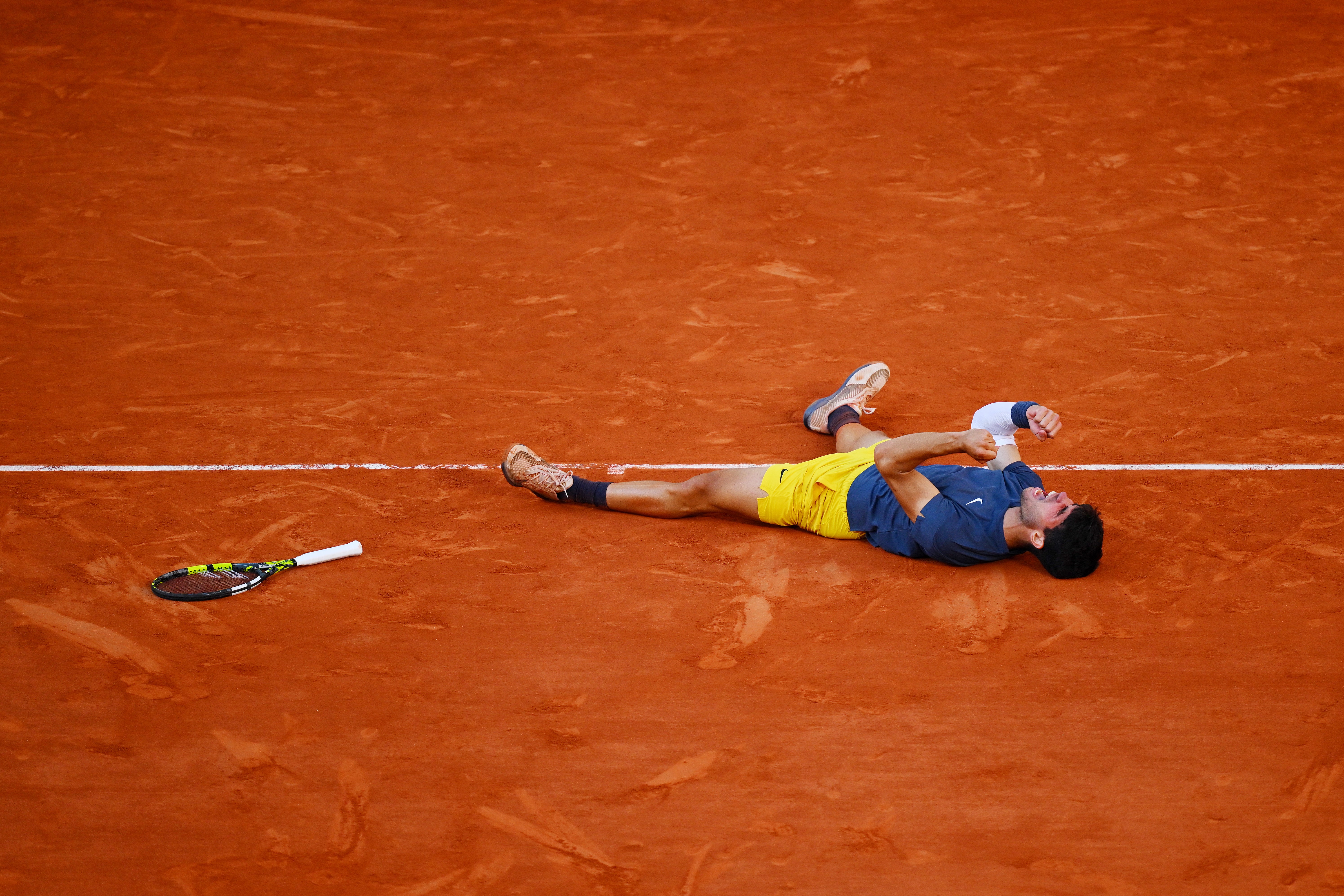 Carlos Alcaraz falls to the clay after winning the French Open for the first time