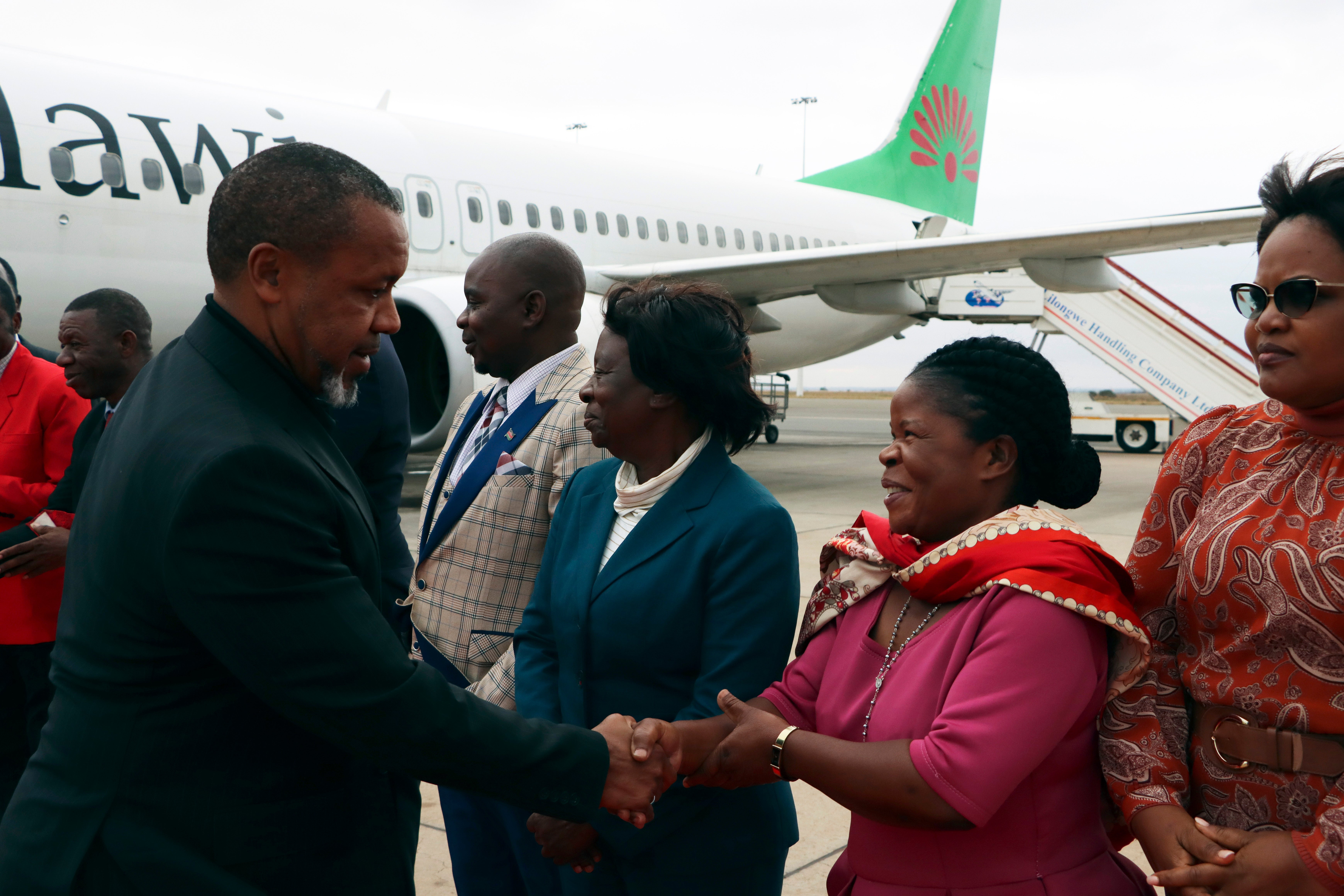 Malawi vice-president Saulos Chilima, left, greets government officials upon his return from South Korea