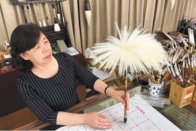 <p>An artisan shows one of the best writing brushes produced by the Shanlian Huzhou Ink Brush Factory</p>