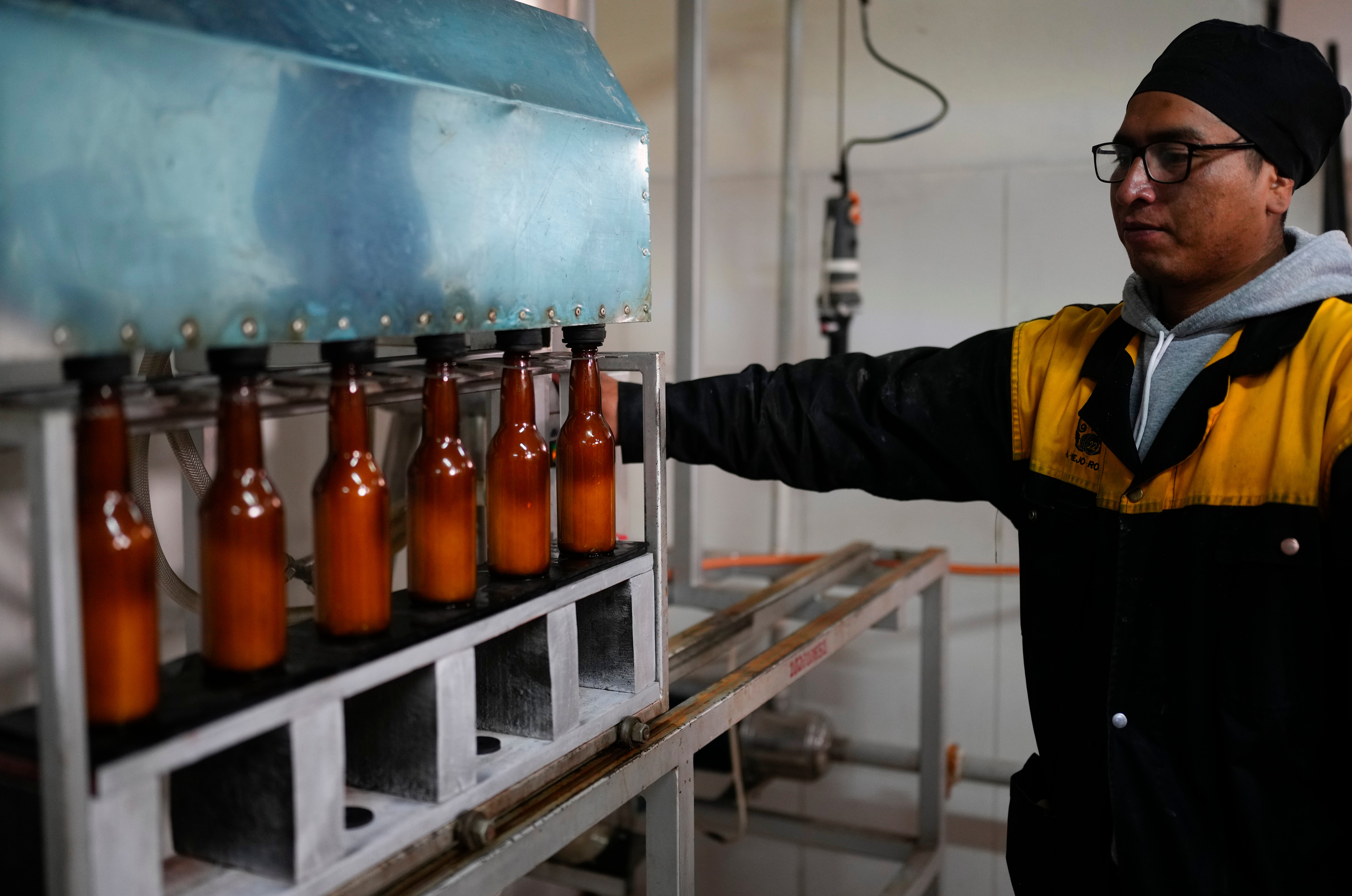 A worker monitors coca leaf-flavored beer bottles on the assembly line at El Viejo Roble liqueurs in La Paz, Bolivia