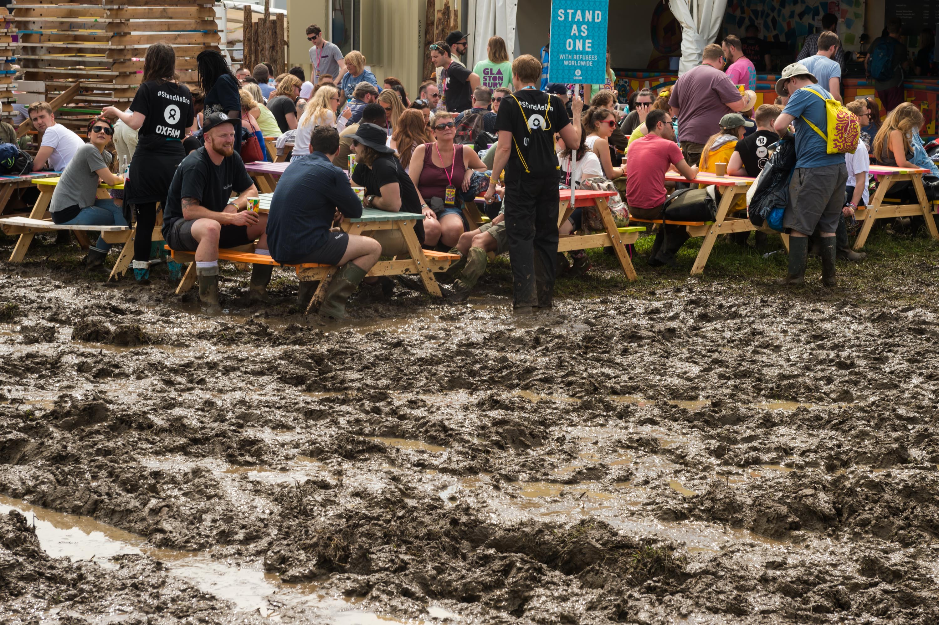 Festival-goers eating lunch in the thick mud in 2016