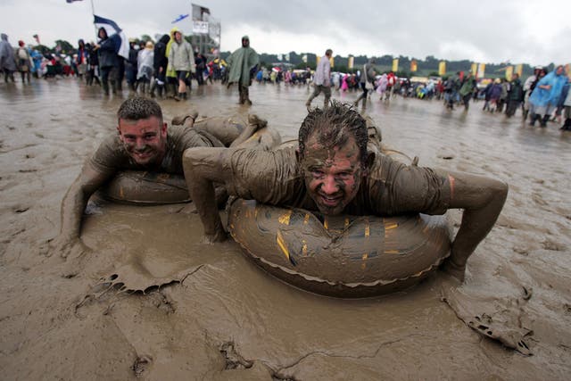 <p>Two festival-goers sliding in the mud at 2007’s Glastonbury festival </p>
