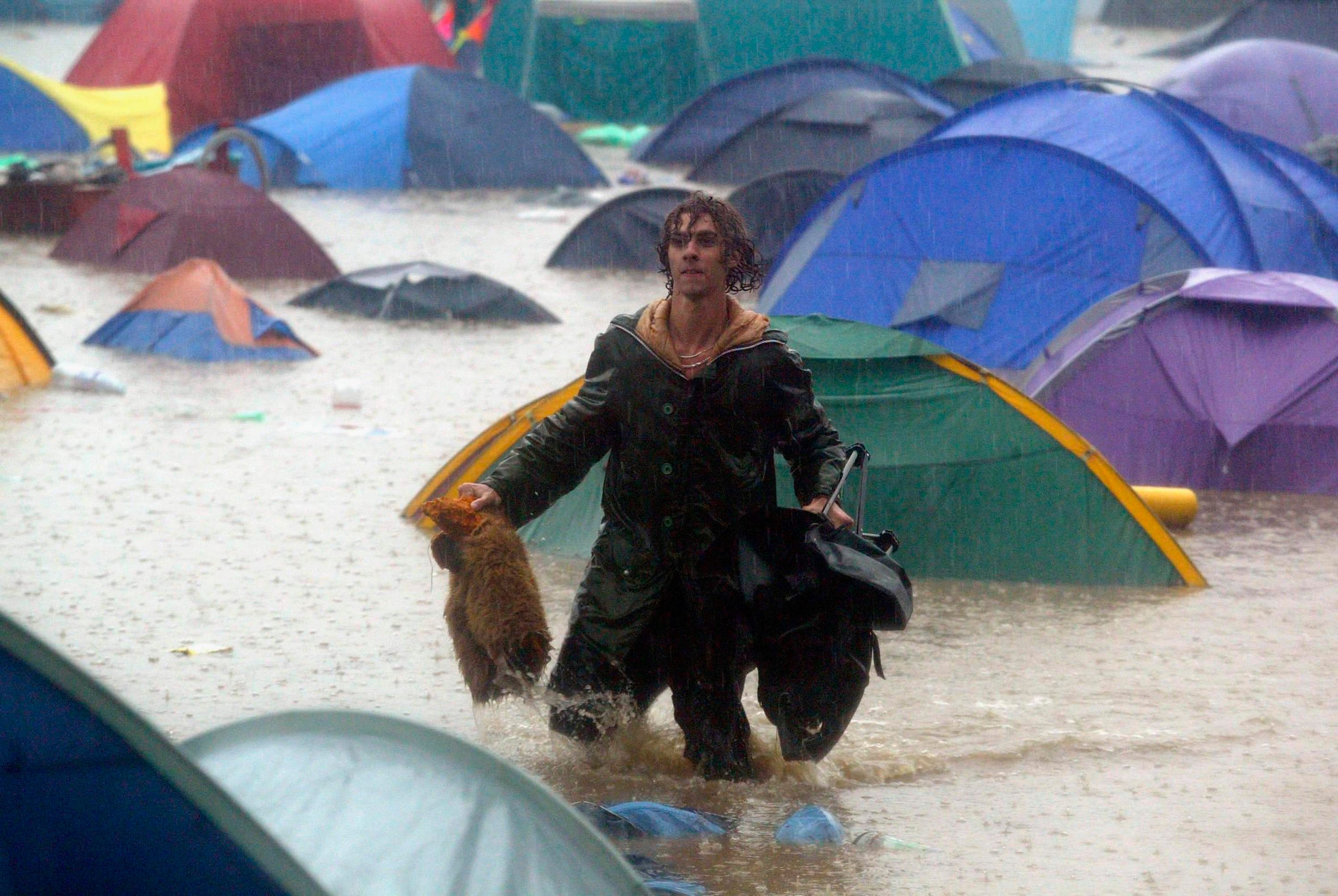 One unlucky festival-goer traipses through a sea of water and abandoned tents during 2005’s festival floods
