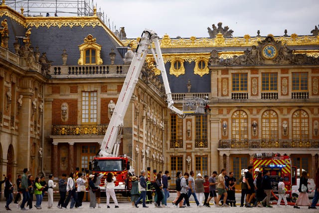 <p>Visitors walk past as French firefighters work after a fire broke out at the Chateau de Versailles </p>
