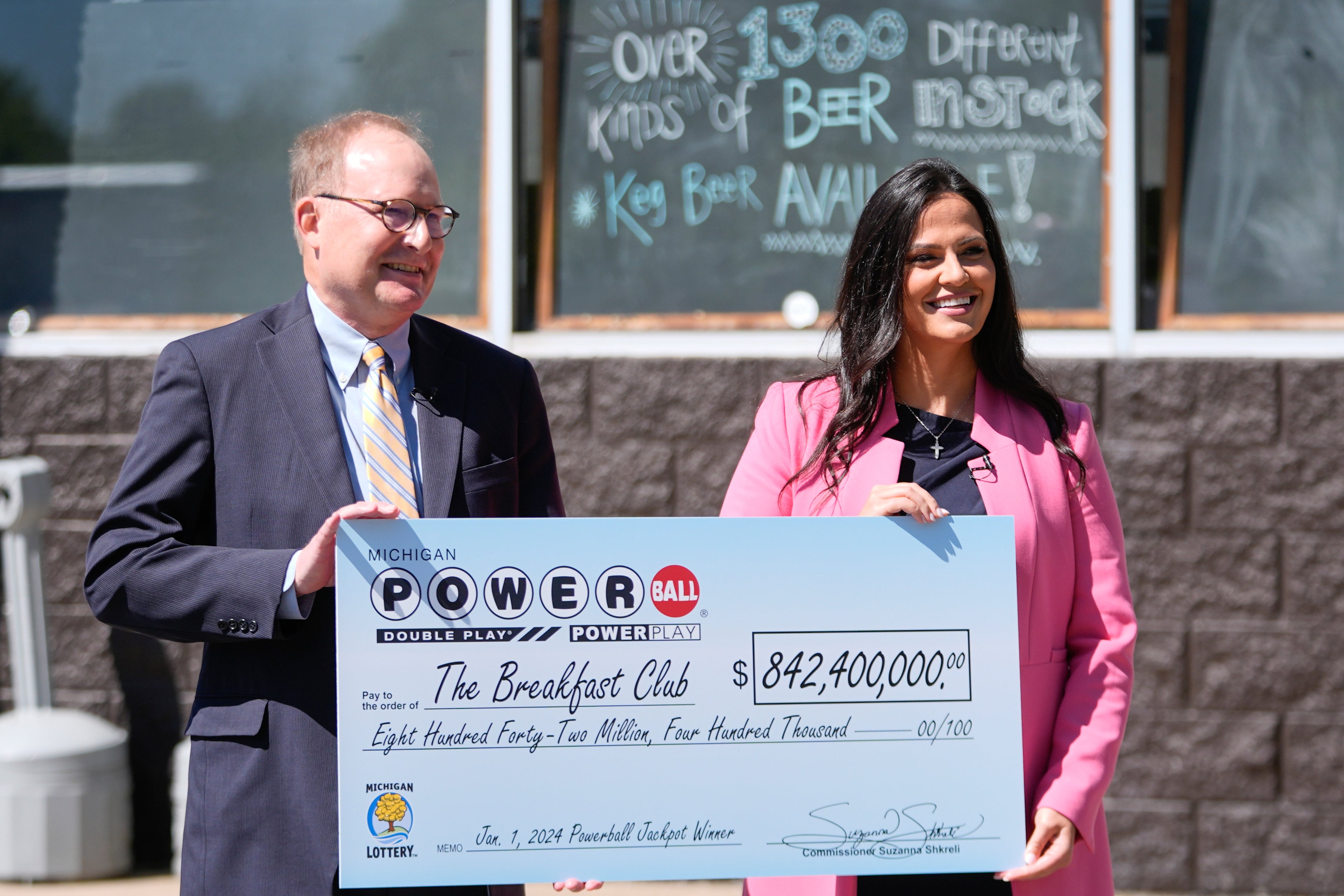 Attorney Mark K. Harder, left, representative of The Breakfast Club, and Michigan Lottery Commissioner Suzanna Shkreli hold an an enlarged check for the $842.4 million Powerball jackpot. The club was announced Tuesday at the lucky winners.