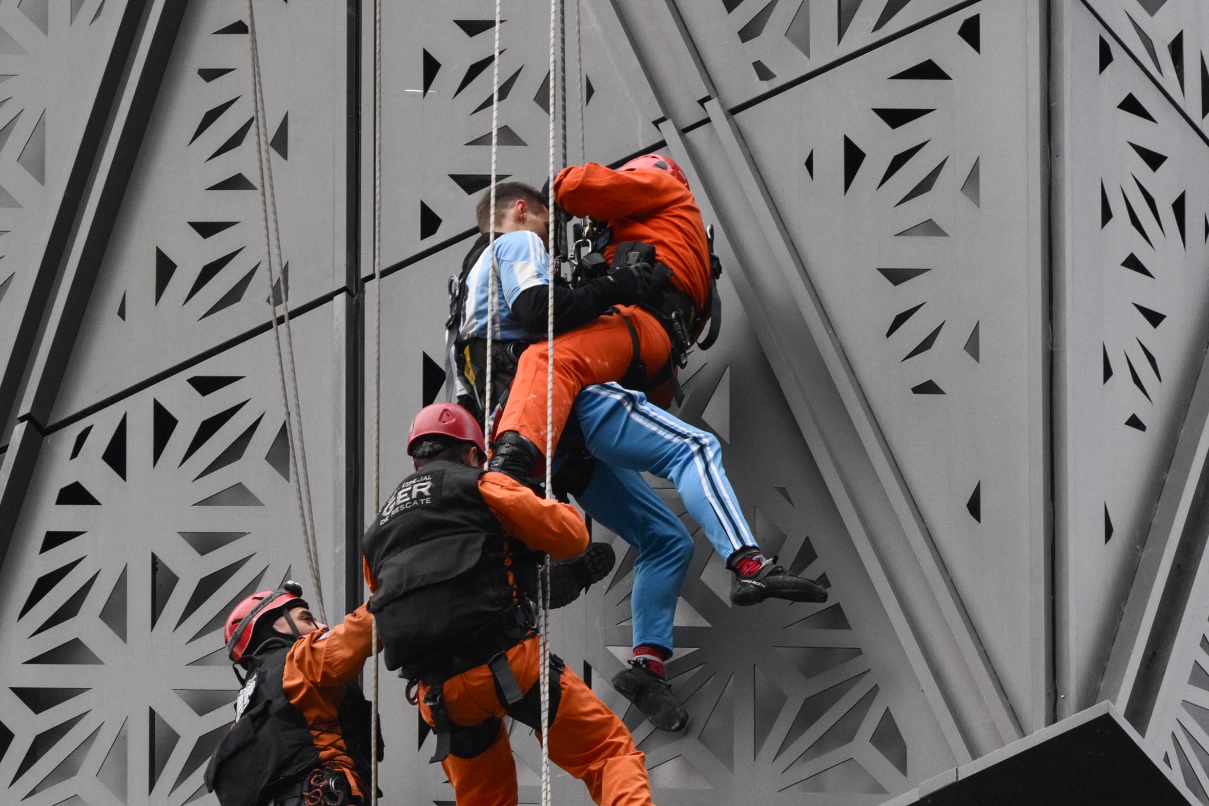 Los bomberos interceptan al escalador polaco Marcin Banot (segundo desde la derecha) mientras escalaba un edificio en Puerto Madero.