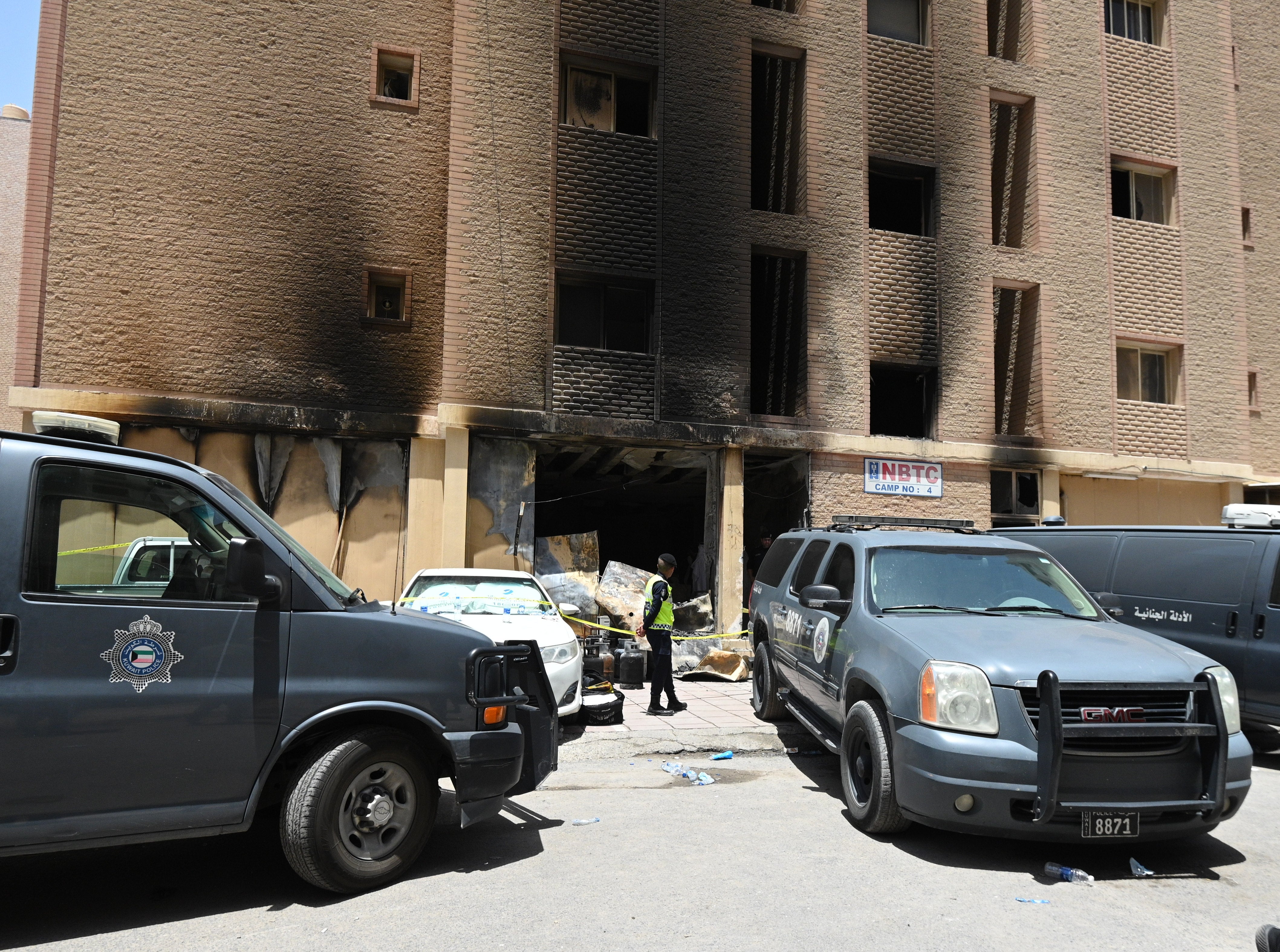 A Kuwaiti policeman stands in front of a residential building after a fire broke out in Mangaf area, southern Ahmadi governorate, Kuwait, 12 June 2024