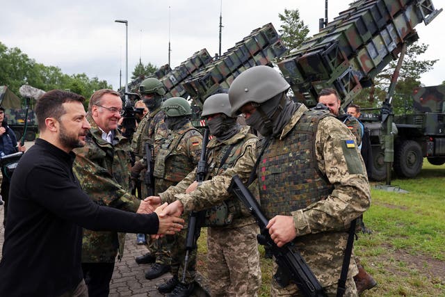 <p>Volodymyr Zelenskyy, left, and German defence minister Boris Pistorius, second left, greet German and Ukrainian soldiers during their visit to a military training area to learn about the training of Ukrainian soldiers on the ‘Patriot’ air defence missile system (Jens Buettner/dpa via AP)</p>