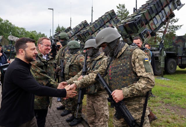 <p>Volodymyr Zelenskyy, left, and German defence minister Boris Pistorius, second left, greet German and Ukrainian soldiers during their visit to a military training area to learn about the training of Ukrainian soldiers on the ‘Patriot’ air defence missile system (Jens Buettner/dpa via AP)</p>